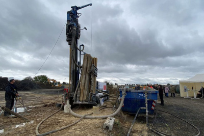 Geothermie Probebohrung: Bohrmaschine mit Arbeiter unter grauem Himmel.