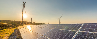 Photovoltaikanlage auf Freifläche mit Windkraft im Hintergrund